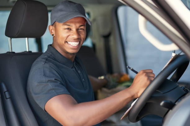 Portrait of a courier writing on a clipboard while sitting in his van